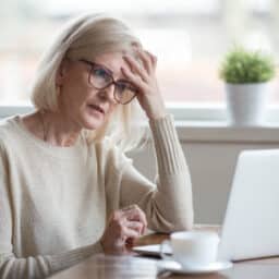 Woman feeling stressed and fatigued while working on laptop.