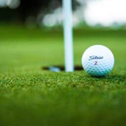 Golf ball sitting next to the hole on the green.