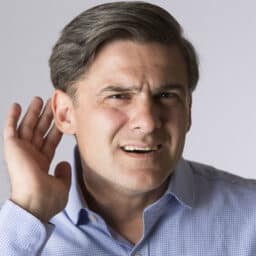 Man with hearing loss holds hand behind ear