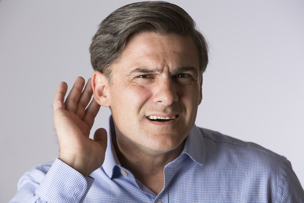 Man with hearing loss holds hand behind ear