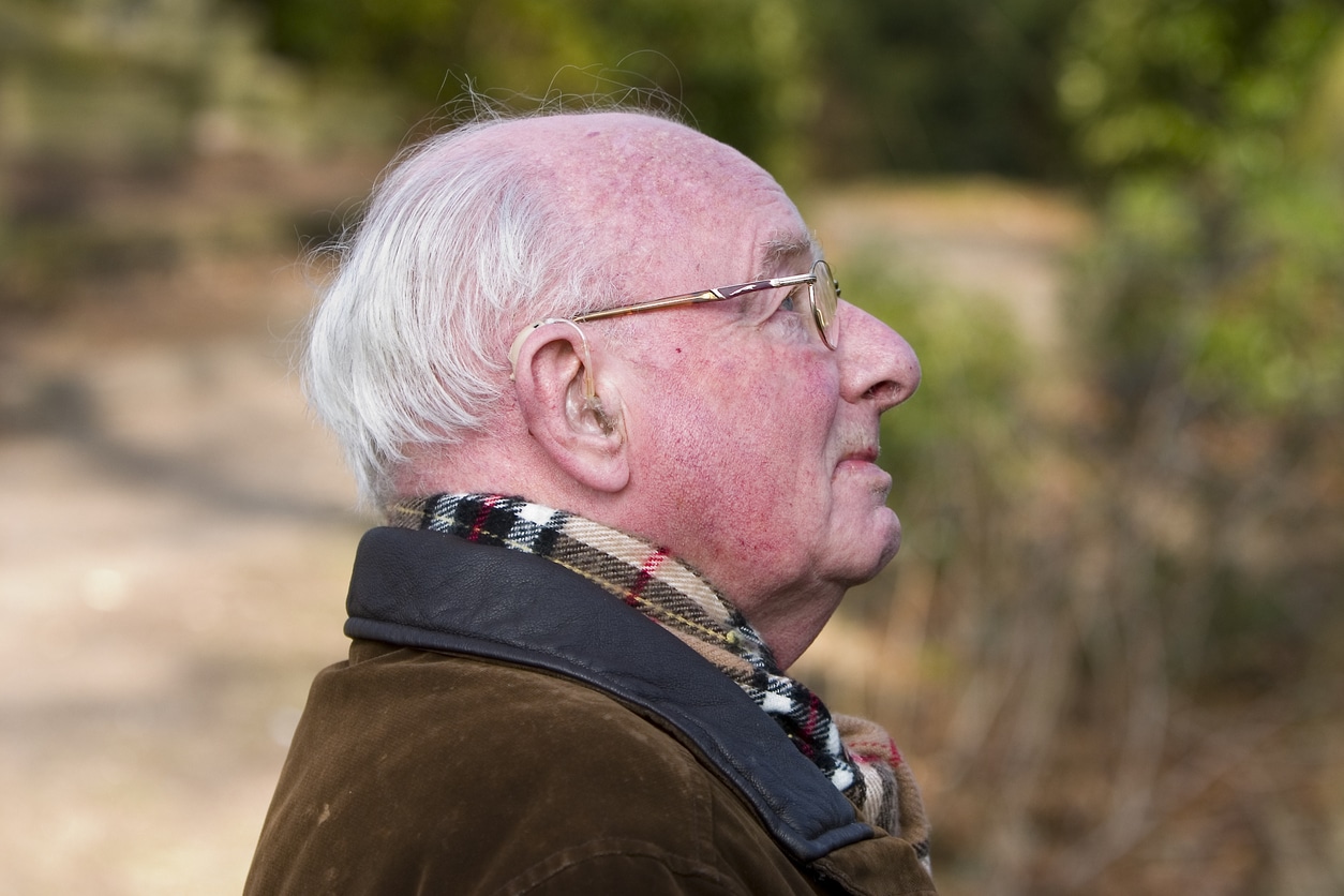Senior man wearing his hearing aid in the chilly weather.