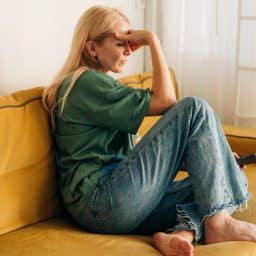 Anxious woman sitting on the couch holding her forehead
