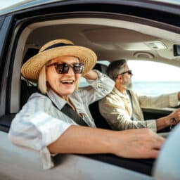 Senior woman leaning through car window while enjoying ride with her husband